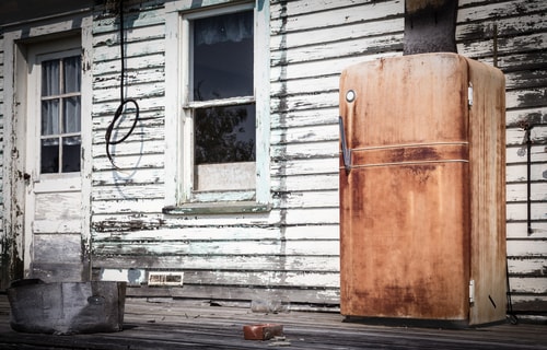 a rusty refrigerator on the porch